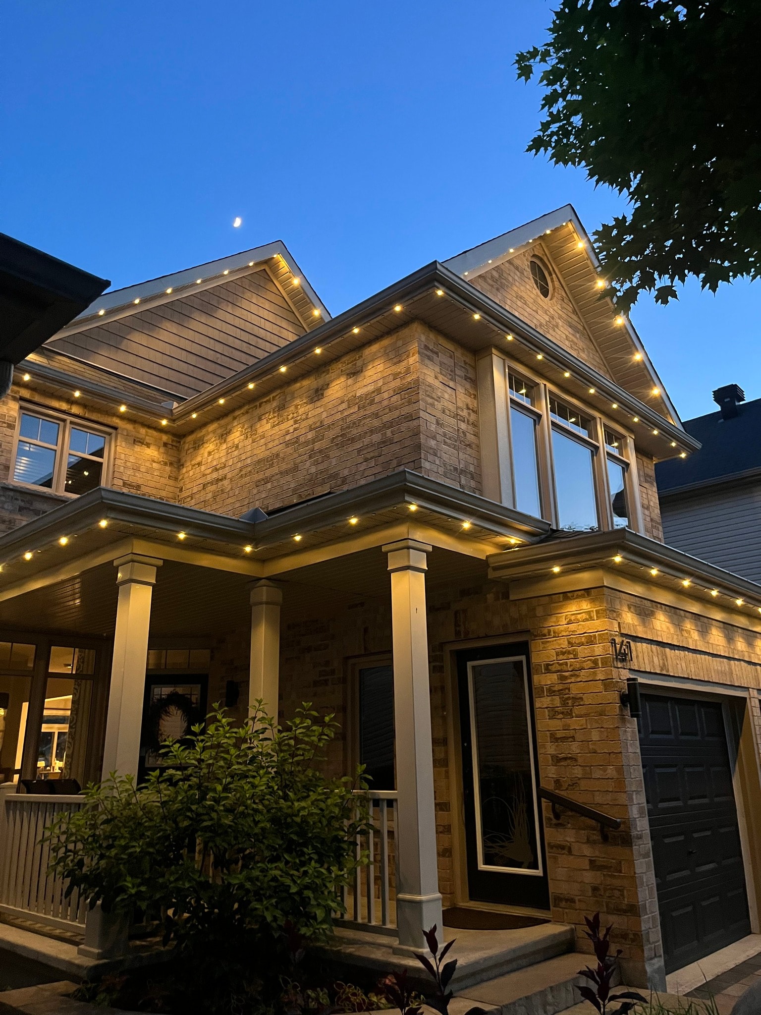 Brick craftsman home with permanent warm white roofline LED lighting at dusk