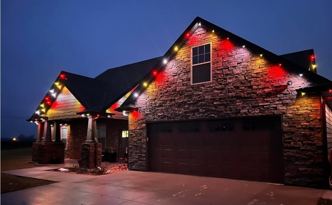 Stone craftsman home with permanent red and gold roofline LED lighting at night
